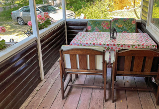 Acogedora terraza con muebles de madera y flores en casa de vacaciones para 6 personas en Rimforsa, Suecia.