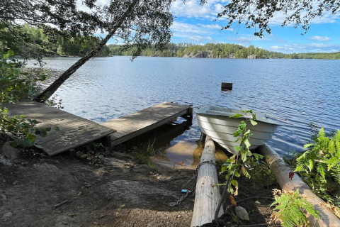 Blick auf einen See von einem Holzsteg mit Ruderboot bei einer Lodge in Rimforsa, Schweden, Natur pur.