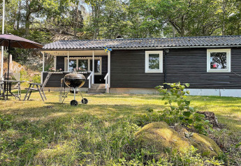 Buitenzone van vakantiehuis voor 6 personen in Rimforsa, Zweden, met barbecue en tuinset.