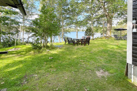 Groene tuin met buitenzitje en uitzicht op een meer bij een vakantiehuis in Rimforsa, Zweden.