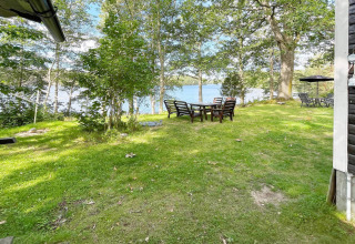 Jardín con césped y áreas de descanso al aire libre con vista al lago, en casa de vacaciones en Rimforsa, Suecia.
