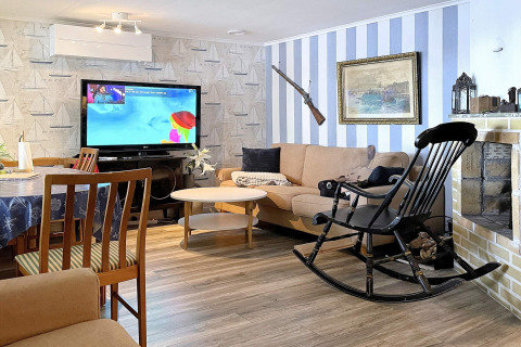 Wohnzimmer eines Ferienhauses in Rimforsa, Schweden, mit Fernseher, Sofa, Schaukelstuhl und Kamin.