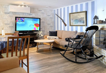 Salon d'une maison de vacances à Rimforsa, Suède, avec télévision, canapé, fauteuil à bascule et cheminée.