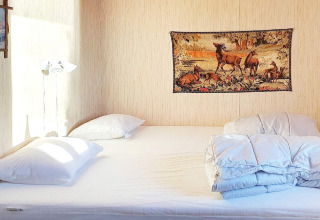 Dormitorio con cama doble, almohadas blancas, edredón y tapiz de ciervos en la pared en Rimforsa, Suecia.