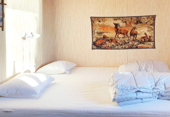 Dormitorio con cama doble, almohadas blancas, edredón y tapiz de ciervos en la pared en Rimforsa, Suecia.