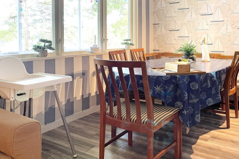 Comedor luminoso en casa de vacaciones en Rimforsa, Suecia, con sillas de madera, trona y decoración náutica.