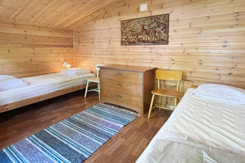 Accogliente camera con due letti singoli, pareti in legno e cassettiera in una casa vacanze a Rimforsa, Svezia.