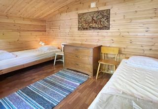 Acogedor dormitorio con paredes de madera, dos camas individuales y cómoda en casa de vacaciones en Rimforsa, Suecia.