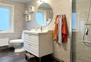 Moderne badkamer in een vakantiehuis in Rimforsa, Zweden, met ronde spiegel en kleurrijke handdoeken.
