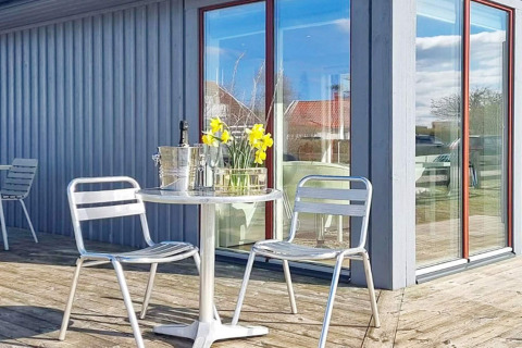 Buitenterras met metalen stoelen, ronde tafel, bloemen, ijsemmer en glazen aan een vakantiewoning in Löttorp, Zweden