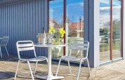 Terrasse extérieure avec chaises en métal, table ronde, fleurs, seau à glace et verres à Löttorp, Suède