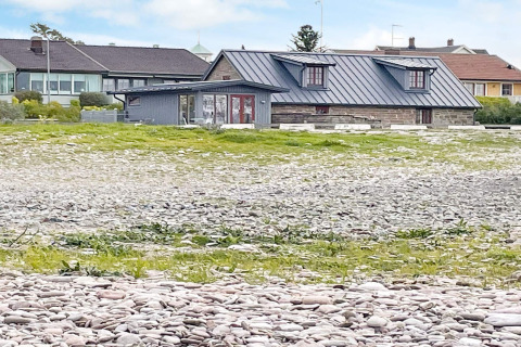 Vakantiehuis in Löttorp, Zweden, met stenen fundering en uitzicht op gras en keien op de voorgrond.
