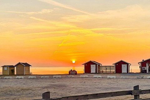 Zonsondergang bij kleine kusthuisjes aan ‘3 person holiday home in LÖTTORP’ in Zweden.