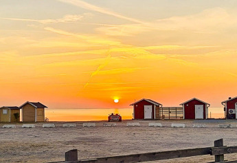 Sonnenuntergang am Strand mit kleinen Hütten beim „3 person holiday home in LÖTTORP“ in Schweden.