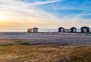 Zonsondergang bij het strand van Löttorp, Zweden, met kleine vakantiehuisjes en een rustige zee.