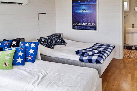 Slaapkamer in een 3-persoons vakantiehuis in Löttorp, Zweden, met twee bedden en opvallende kussens.