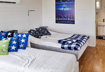 Dormitorio en casa de vacaciones para 3 personas en Löttorp, Suecia, con dos camas y cojines decorativos.