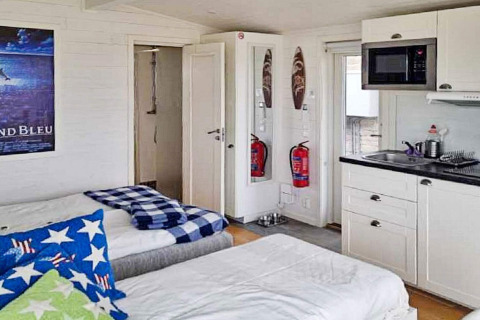 Vista interior de una cabaña vacacional para 3 personas en Löttorp, Suecia, con camas, cocina y extintores.