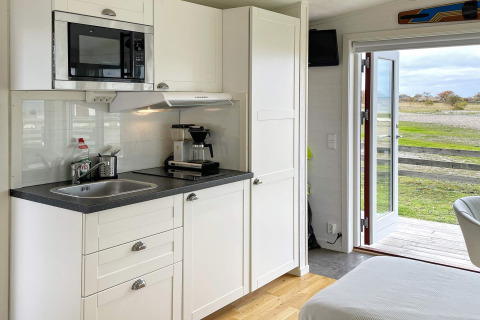 Moderne keuken in een 3-persoons vakantiehuis in Löttorp, Zweden, met witte kasten en buitenzicht.