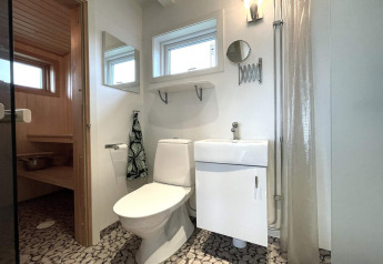 Baño moderno con sauna, inodoro y lavabo en una casa de vacaciones para 3 personas en Löttorp, Suecia.