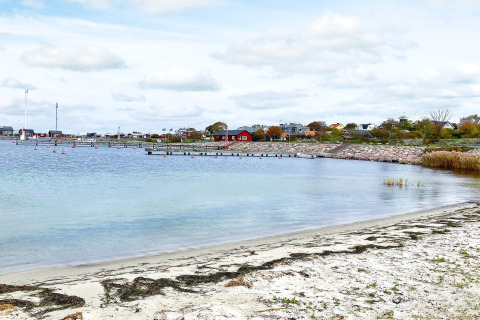 Vista da una casa vacanze a Löttorp, Svezia, con spiaggia sabbiosa, casette e acqua tranquilla.
