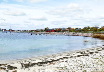 Vista desde una casa de vacaciones en Löttorp, Suecia, con playa de arena, cabañas y agua tranquila.