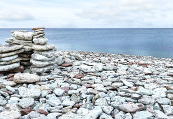Steinhaufen am Ufer bei Löttorp, Schweden, mit Blick auf das ruhige Meer und bewölkten Himmel.