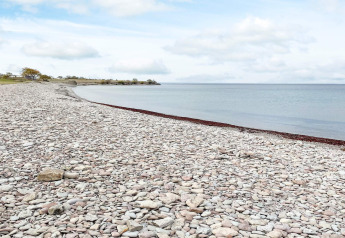 Plage rocailleuse et mer calme près du gîte à Löttorp, Suède, sous ciel couvert.