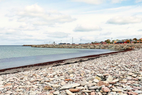 Plage de galets et vue sur la côte près d'une maison de vacances à Löttorp, Suède, sous un ciel dégagé.