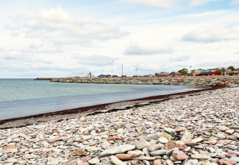 Stenstrand og kystudsigter i nærheden af en feriebolig i Löttorp, Sverige, med hav og farverige huse.