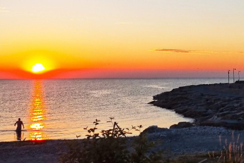 Tramonto sul mare visto dal 3 person holiday home in LÖTTORP, Svezia, con persona in acqua.