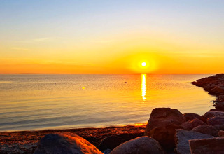 Coucher de soleil sur une mer calme et des rochers, vu depuis un gîte 3 personnes à Löttorp, Suède.