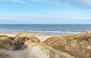 Vista desde las dunas en la playa de Pandrup, Dinamarca, con el mar y el cielo azul al fondo.
