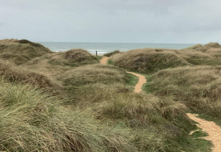 Kronkelend pad tussen grasduinen naar zee vlakbij ‘6 persoons vakantiewoning in Pandrup’, Denemarken.