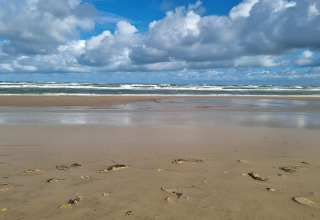Spiaggia sabbiosa con onde e cielo nuvoloso vicino a Pandrup, Danimarca, vista da una casa vacanze.