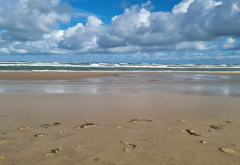 Plage de sable avec vagues et ciel nuageux près de Pandrup, Danemark, vue depuis un gîte de vacances.