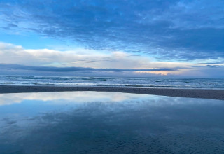 Schitterend zicht op zee, lucht en hun weerspiegeling in het water op een strand in Pandrup, Denemarken.