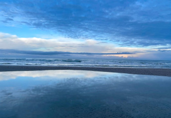 Schitterend zicht op zee, lucht en hun weerspiegeling in het water op een strand in Pandrup, Denemarken.
