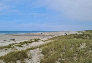 Vue depuis les dunes sur la large plage de Pandrup, Danemark, avec quelques voitures et personnes.