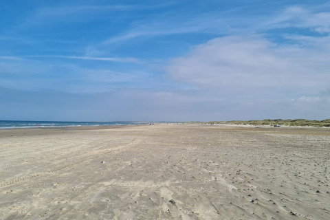 Zicht op een brede zandstrand bij zee, genomen dicht bij het 6-persoons vakantiehuis in Pandrup, Denemarken.