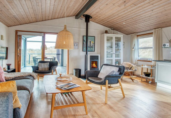 Salon confortable d'une maison de vacances pour 6 personnes à Pandrup, Danemark, avec cheminée et meubles en bois.