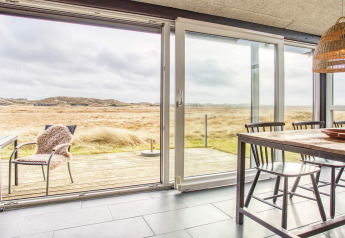 Eetruimte met grote ramen en uitzicht op het landschap in het 6-persoons vakantiehuis in Pandrup, Denemarken