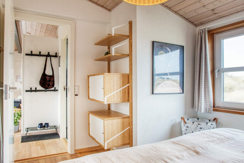 Lichte slaapkamer in vakantiehuis in Pandrup, Denemarken, met houten vloer en moderne wandkast.
