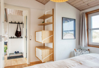 Dormitorio luminoso en casa de vacaciones en Pandrup, Dinamarca, con madera y estantería moderna.