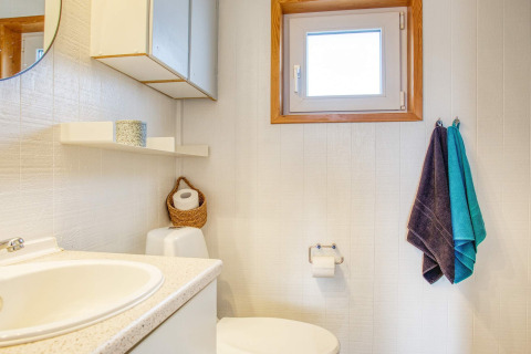 Bagno luminoso e semplice con lavabo, asciugamani, wc e finestra in una casa vacanze a Pandrup, Danimarca.