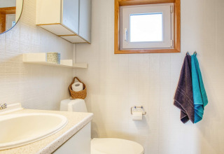 Bagno luminoso e semplice con lavabo, asciugamani, wc e finestra in una casa vacanze a Pandrup, Danimarca.