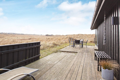 Holzterrasse an einem Ferienhaus für 6 Personen in Pandrup, Dänemark, mit weitem Ausblick ins Grüne.