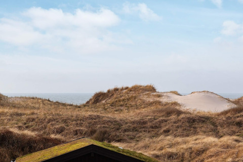Blick auf Dünen und Meer vom 6-Personen-Ferienhaus in Pandrup, Dänemark, bei blauem Himmel.