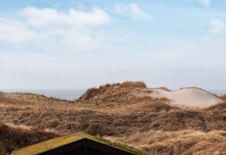 Uitzicht op duinen en zee vanuit een 6-persoons vakantiehuis in Pandrup, Denemarken, blauwe lucht.