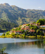 Parco vacanze con sistemazioni glamping vicino a un lago, incorniciato da montagne e foreste verdi.